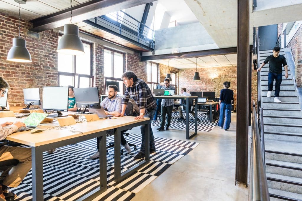 De nombreux collaborateurs travaillent dans un open space au design mélangeant bois et pierres